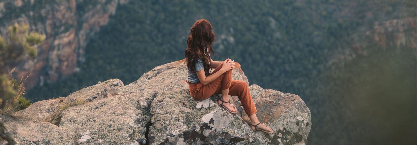 Woman overlooking a mountain landscape representing emotional fitness, emotional resilience, self-mastery, and recovery from people-pleasing.