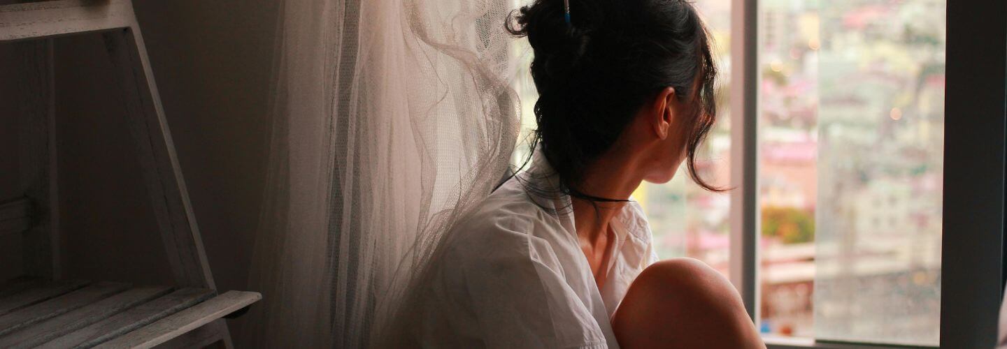 Woman sitting quietly by a window, symbolizing the signs your intuition is getting stronger, trusting your gut feeling, and reconnecting with your inner knowing.
